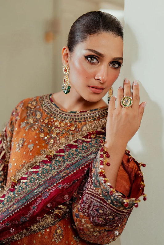 Jazmin Bridal Wear PAkistani Dress Woman in traditional embroidered outfit with jewelry, posing indoors.