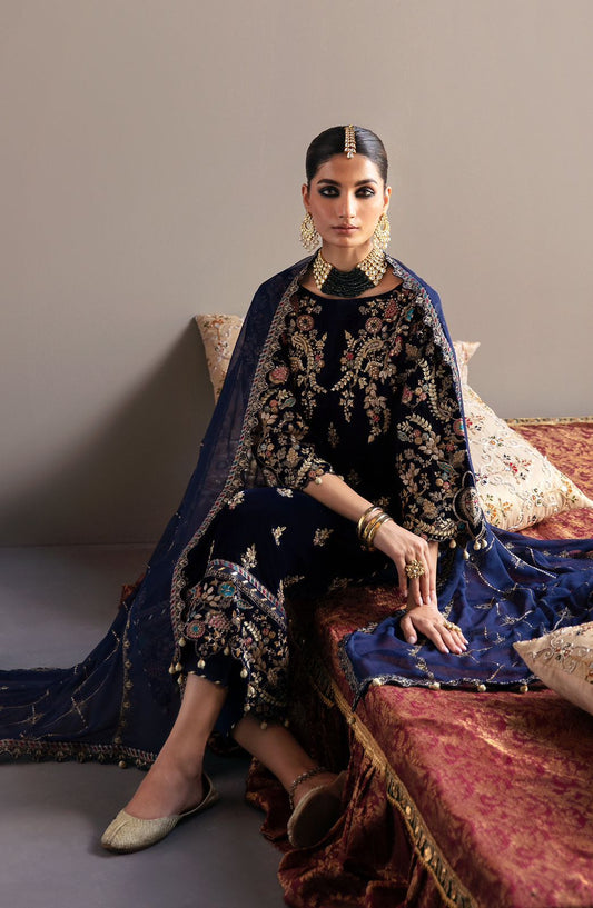 Emaan Adeel  Velvet  Woman in traditional attire sitting on a decorative couch against a plain background