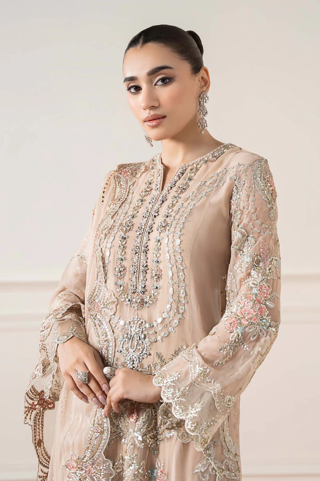 Maria b Formal & Wedding Woman wearing a beige embroidered dress with floral patterns on a light background