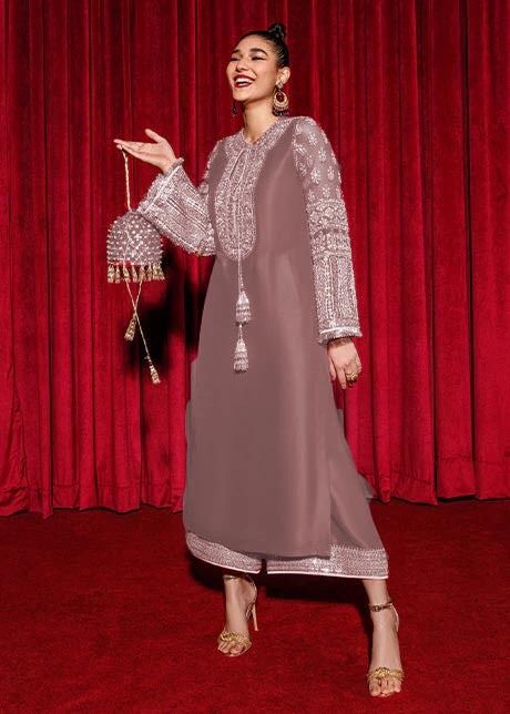 Hussain Reher Dress With Clutchin a traditional outfit with intricate designs against a red curtain background
