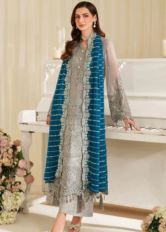 Noori By imrozia traditional outfit with blue and white patterns standing in front of a piano